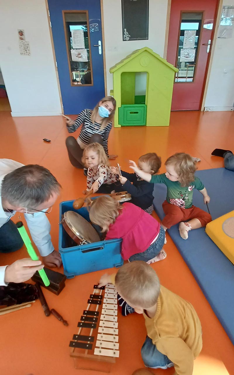 Des professeurs de l'école de musique et des enfants avec une caisse d'instruments de musique au relais petite enfance de Pouilly en Auxois